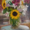 A vase of flowers set on a table outside, with a sunflower in the center, reminding me of a child say "Look At Me!"