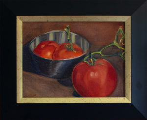 Three bright red tomatoes (two in a reflective stainless steel bowl, one left out on the counter)